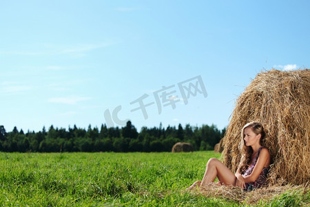 蓝天下一堆干草旁的女孩肖像