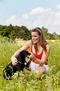 饲养员摄影照片_夏天，一位妇女在草地上和她的狗玩耍