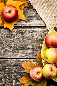 感恩节红色摄影照片_秋天的边缘，木桌上的苹果和枫叶。感恩节的概念