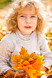 秋天公园里一个有趣的孩子拿着黄色的枫叶