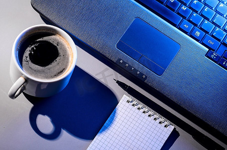 晚上工作，桌上放着笔记本电脑和一杯热咖啡