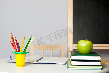 课桌上有苹果、铅笔、笔记本和课本。办学理念