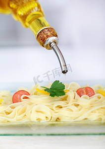 将橄榄油倒在意大利面食上的特写