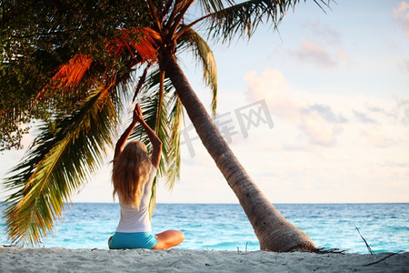 瑜伽大海摄影照片_海边棕榈树下的瑜伽女子