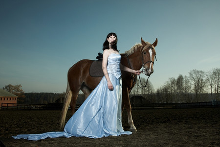 年轻漂亮的女人骑着一匹棕色的马