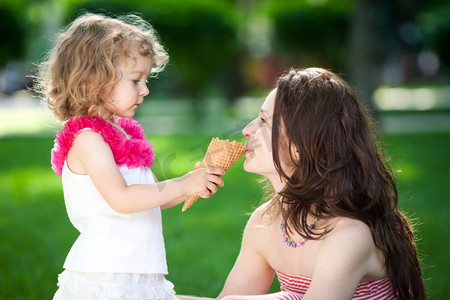 抱着东西的女孩摄影照片_春天公园里吃冰淇淋的妇女和儿童