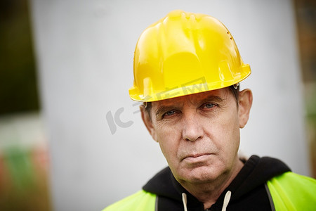 黄色安全帽摄影照片_真正有经验的建筑商，戴着黄色安全帽，自然光