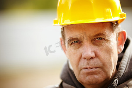 黄色安全帽摄影照片_真正有经验的建筑商，戴着黄色安全帽，自然光