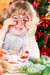 一个有趣的孩子微笑着拿着手工制作的环保装饰品对着圣诞彩灯