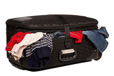 Overstuffed行李在旧手提箱孤立在白色背景
