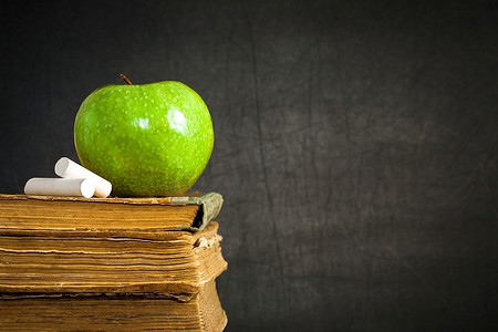 青苹果和粉笔在旧书上衬托着黑板，留出了文本的空间。学校理念
