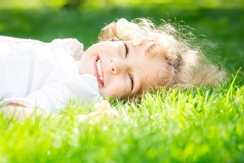 快乐的孩子躺在春天公园的绿草地上