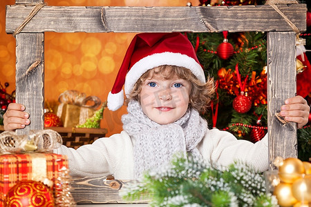 圣诞节小朋友摄影照片_圣诞树背景下抱着木架的快乐小朋友