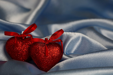 成婚摄影照片_蓝色丝绸背景上的两颗红心