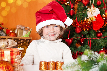 戴着桑塔帽子的快乐孩子靠在圣诞树上装饰