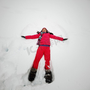 雪摄影照片_冬天的女人躺在雪地上