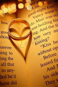 一部浪漫小说中的结婚戒指创造了一个心形的阴影和灯光