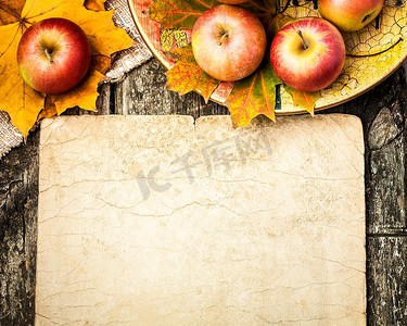 秋天的背景，木桌上的苹果和枫叶。带版面的复古纸板