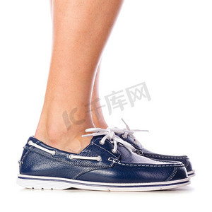 白色背景下赤脚穿的蓝色皮革甲板鞋