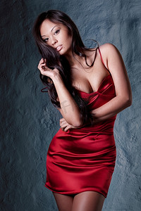年轻漂亮的黑发女子穿着红色晚礼服摆姿势