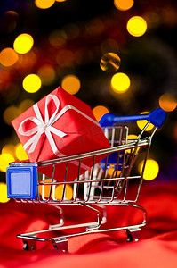圣诞树上带有装饰礼品盒的购物车，以对抗模糊的灯光