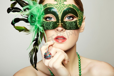 神秘面具人摄影照片_戴着绿色神秘威尼斯面具的美丽年轻女子