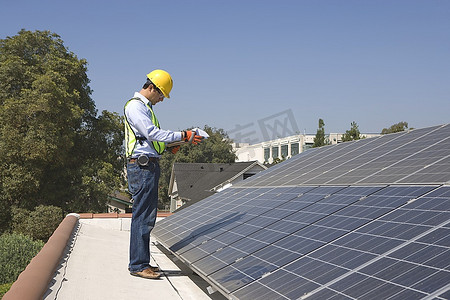 手持式rfid摄影照片_加利福尼亚州洛杉矶，维修人员站在屋顶上，手持太阳能电池板