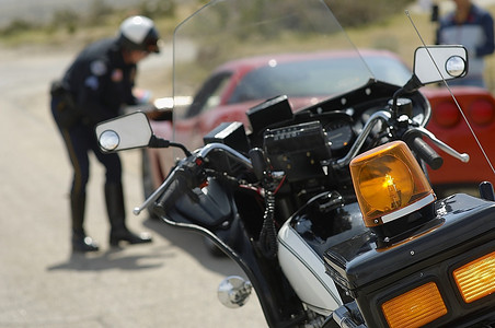 交警与汽车司机交谈，关注前景中的摩托车
