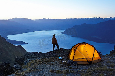 黄昏时分，一名男子在帐篷旁望着湖