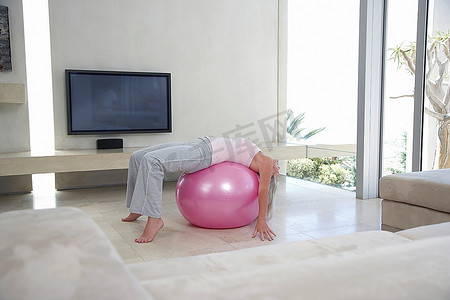 女子在健身球上伸展身体