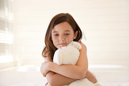 女孩抱着泰迪熊，半长坐在床上