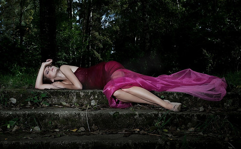 艳丽风景摄影照片_戏剧性的风景，身穿深红色连衣裙的美丽仙女躺着-系列露天照片