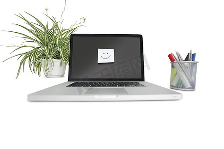 在笔记本电脑上贴上带办公用品和盆栽植物的笑脸贴纸