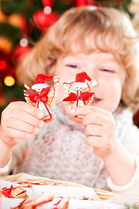 快乐的孩子拿着手工制作的环保装饰品对着圣诞彩灯