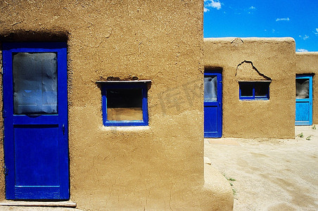 稀疏摄影照片_带有蓝色窗户和门框的土坯房