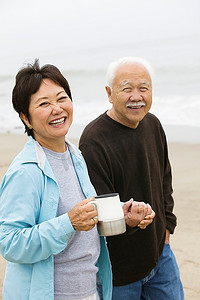 联系方式摄影照片_海滩上的一对老年夫妇手牵着手看着相机
