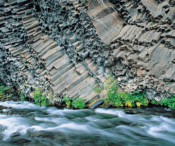 柱状图对比摄影照片_柱状玄武岩悬崖底部的植物与河流