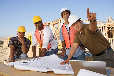 四名建筑工人在建筑工地检查图纸