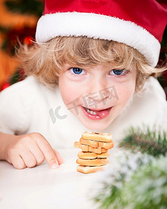 戴着桑塔帽子微笑的孩子吃着圣诞饼干