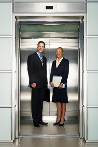 办公室电梯里微笑的商人和女商人