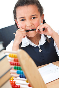 一个年轻漂亮的混血黑人女孩在学校教室里读书，面前摆着一堆书，一个算盘在嚼着铅笔