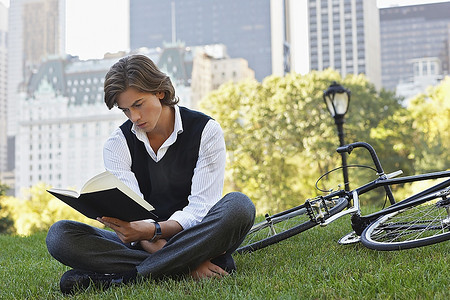 男人坐在草坪上看书