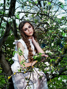 苹果树远景摄影照片_在盛开的苹果树上，年轻性感的女人