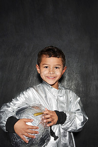 小男孩(5-6)身着宇航员服装，手持头盔微笑摄影棚拍摄