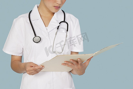 一名女医生在浅蓝色背景下阅读医疗报告的中段