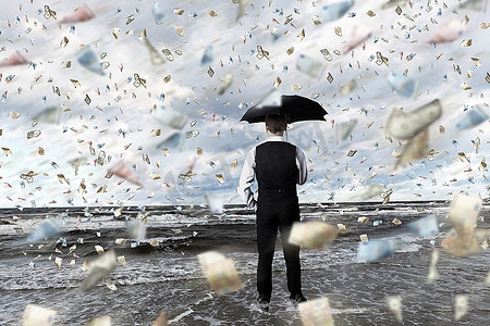 雨中撑伞摄影照片_一位年轻的商人撑着伞站在钱雨中