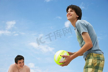 夹角摄影照片_青少年男孩(16-17岁)玩沙滩排球低角度观看