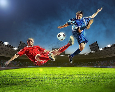 户外运动老外摄影照片_两名足球运动员在体育场跳起来击球。