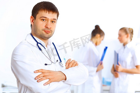 身穿白色制服的年轻男医生，背景是同事