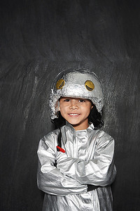 小男孩(5-6)穿着宇航员服装交叉双臂微笑拍摄的肖像